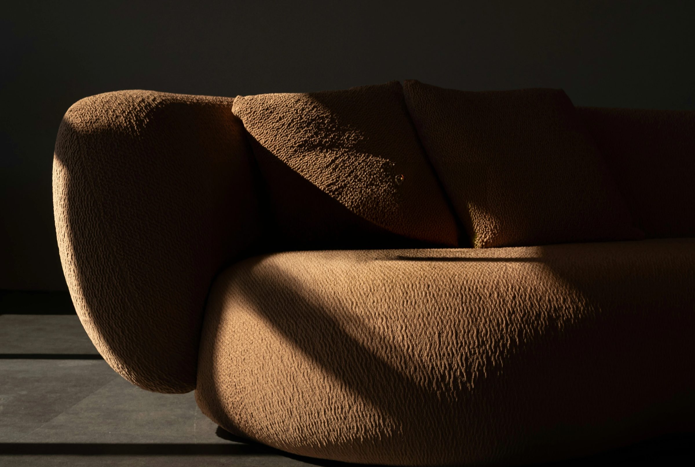 A sculptural bouclé sofa in raking light